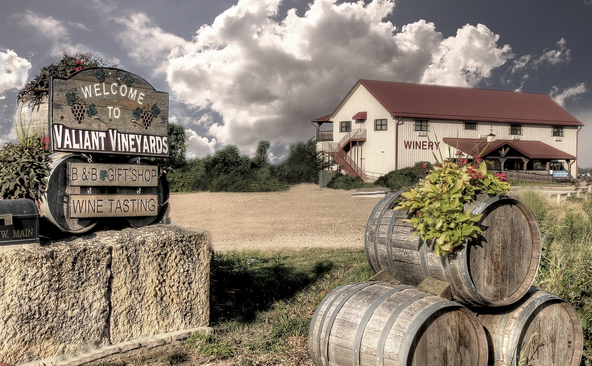 Welcome to Valiant Vineyards - view of the winery entrance with rustic welcome sign and wine barrels